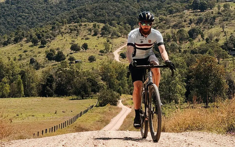 A rider on a gravel trail through green hills in the Brisbane Valley