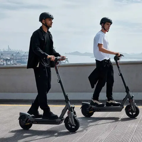 Two riders in helmets on Segway e-scooters