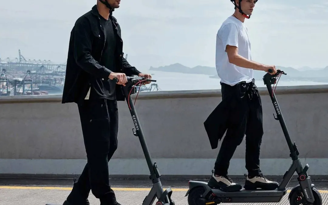 Two riders in helmets on Segway e-scooters by the water in Brisbane