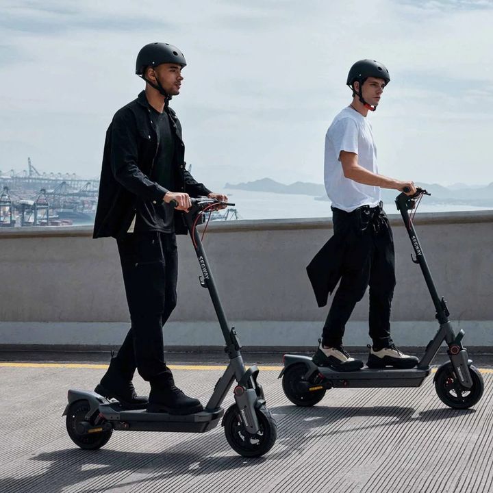 Two riders in helmets on Segway e-scooters