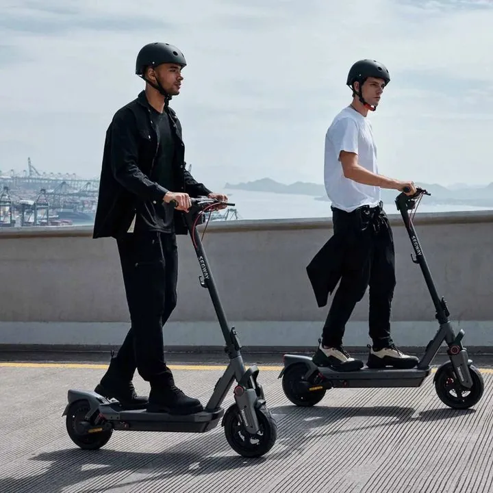 Two riders on Segway e-scooters by the water