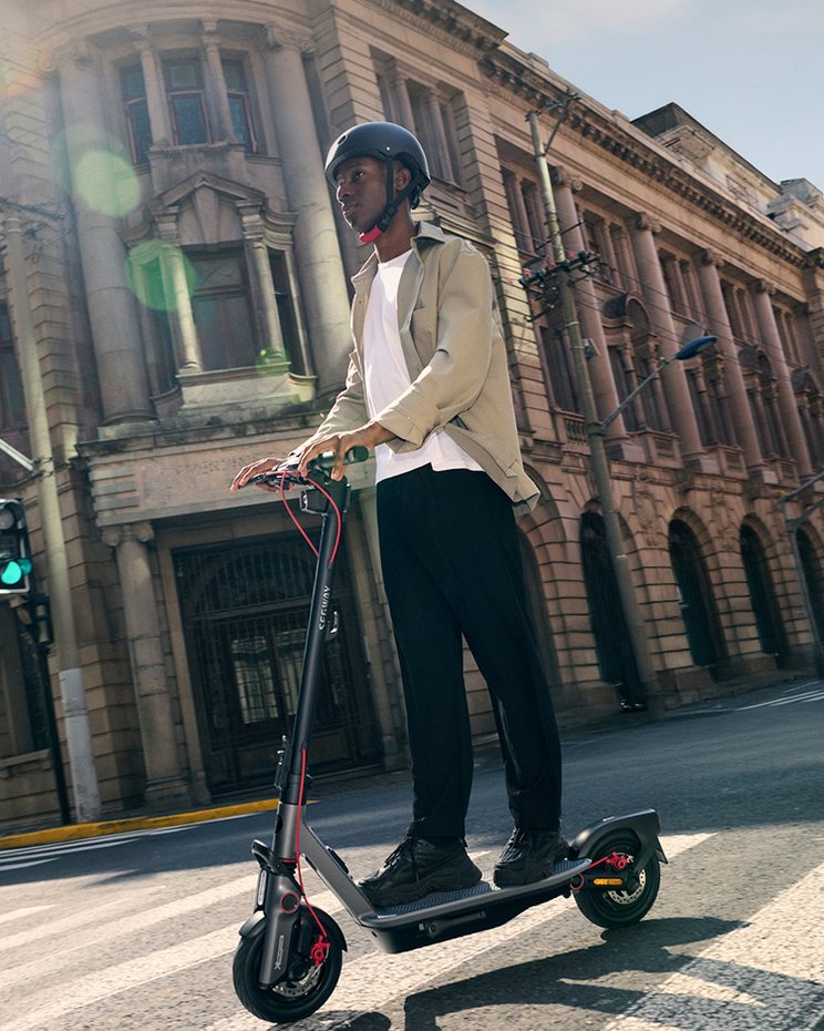 A rider in a helmet on the Segway F3 Pro e-scooter in the city