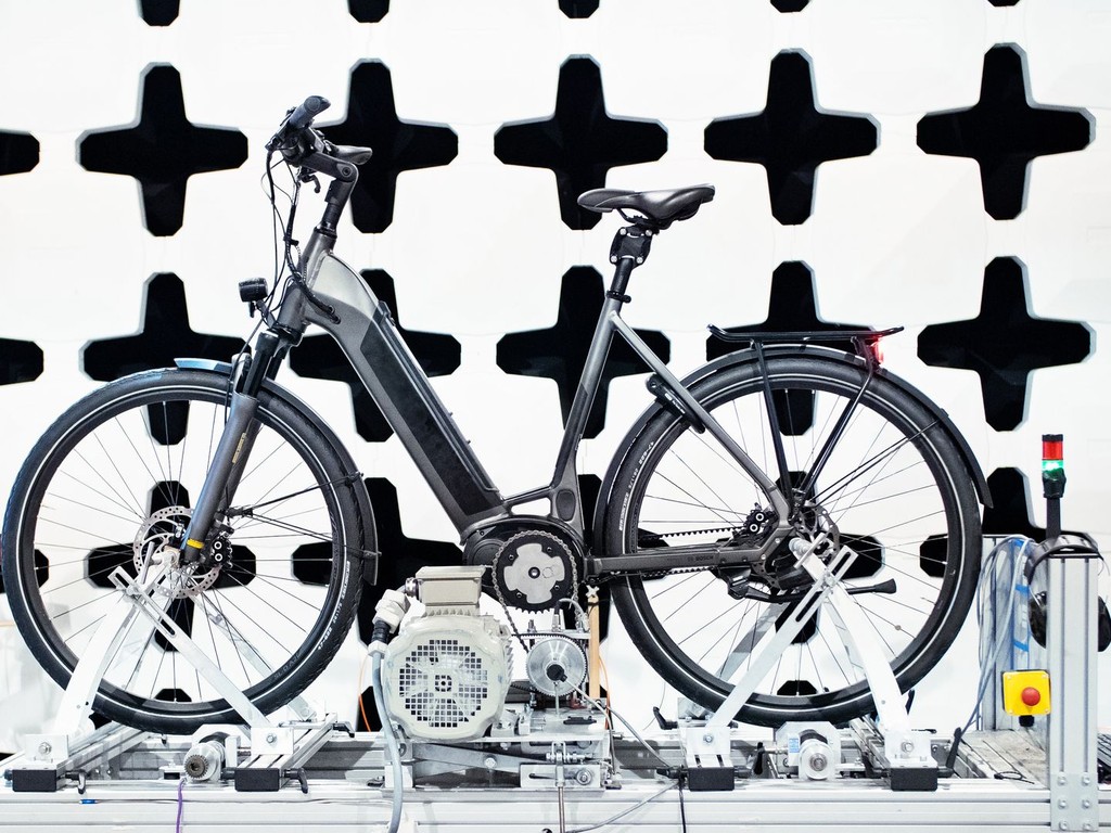 An e-bike undergoing motor and drivetrain testing on a lab dyno rig, part of the qualifying process before a bike earns a place on our floor