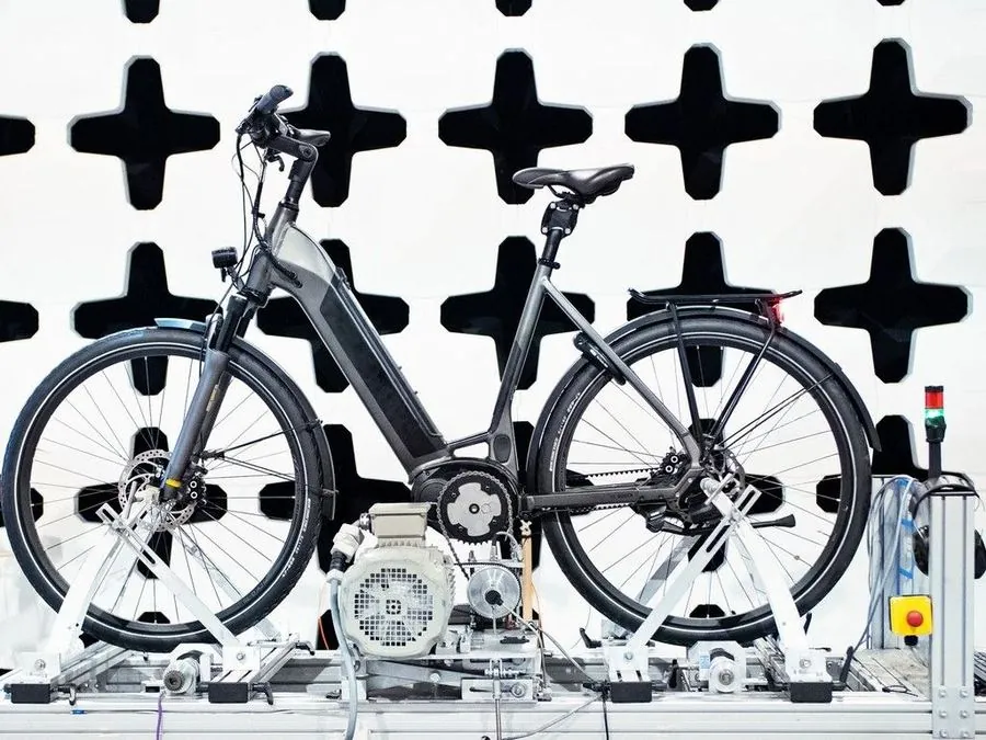 An e-bike undergoing motor and drivetrain testing on a lab dyno rig, part of the qualifying process before a bike earns a place on our floor